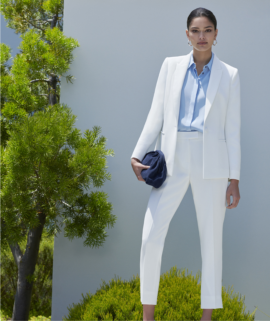 Women’s suit in white, worn with a collared shirt in pale blue, dark navy clutch bag and matching court shoes in dark navy, by Hobbs.