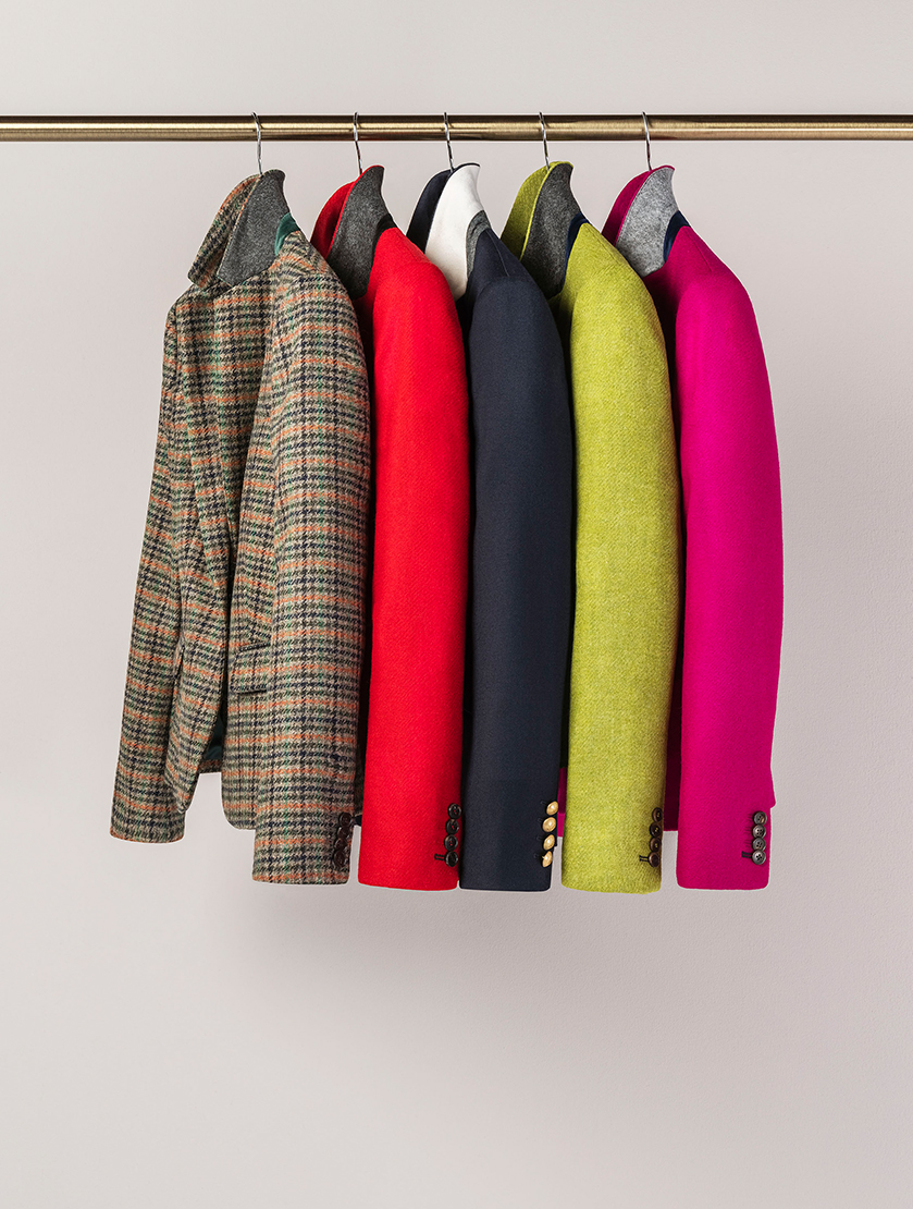 An image of a rail featuring Hobbs jackets made from Abraham Moon’s British made sustainable fabrics. From left to right: Check, red, blue, green and pink.