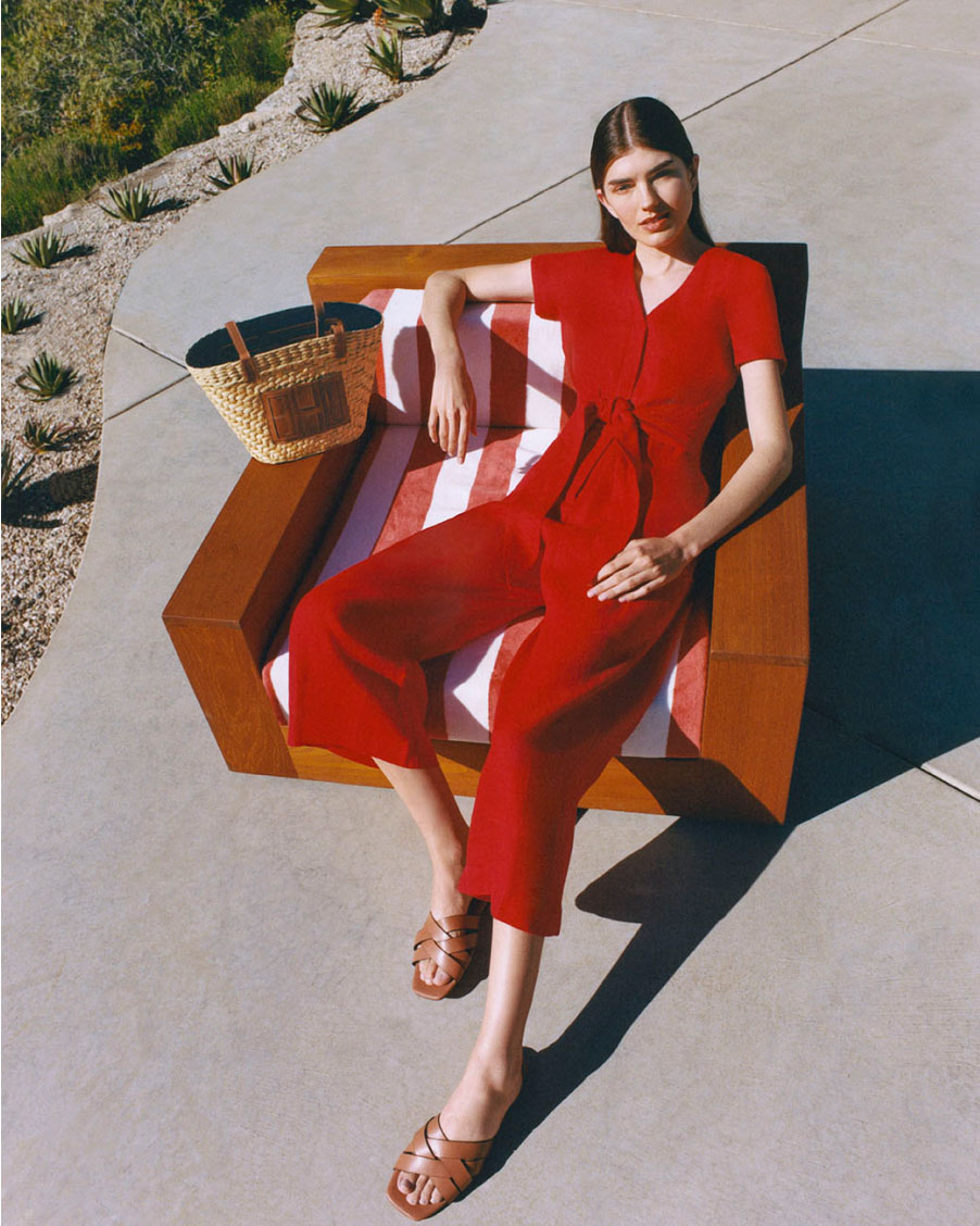 Image of model lounging by a pool, wearing a t-shirt and green linen trousers.