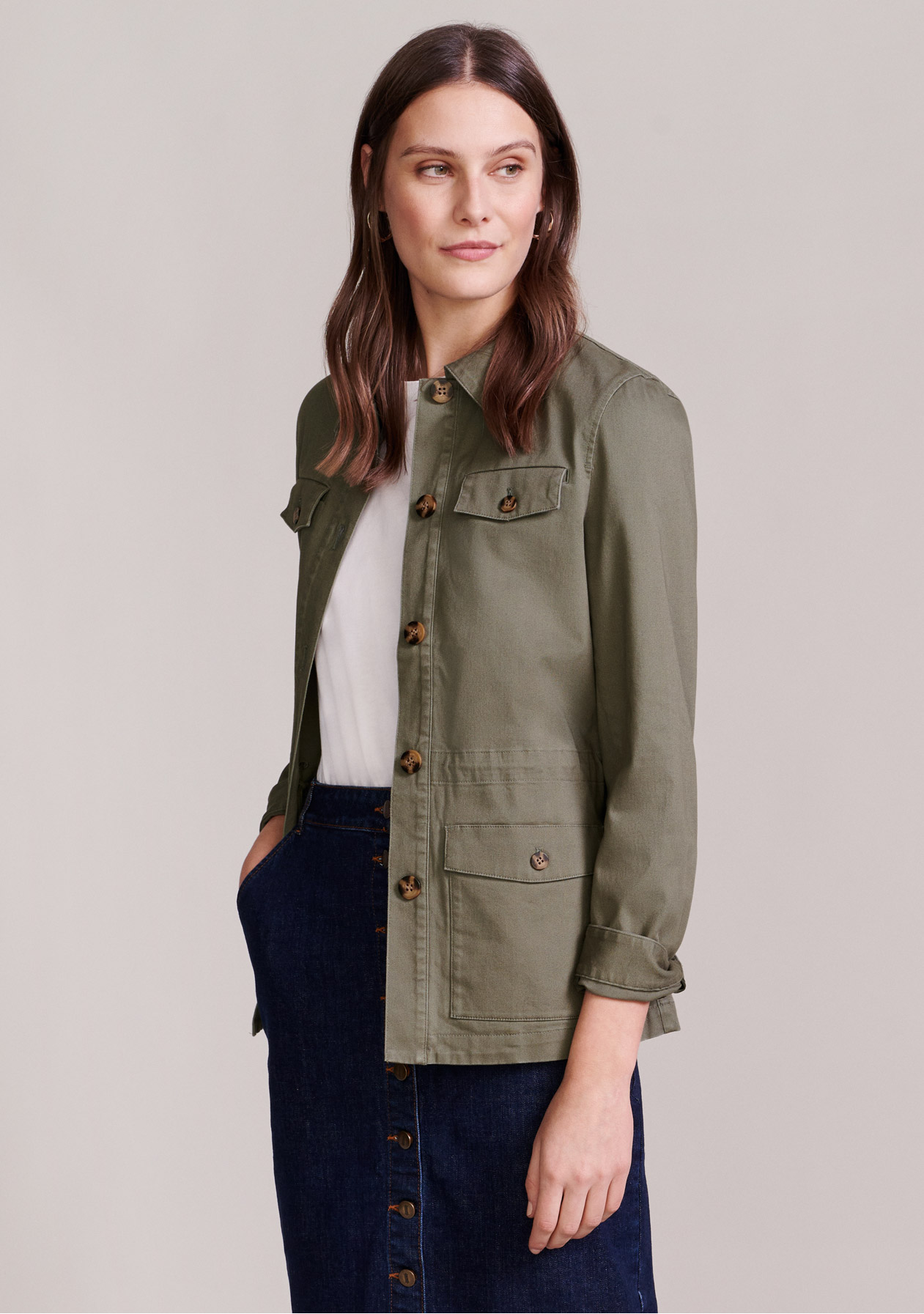 Model wears a khaki field jacket, a white tee and a button-through denim skirt.