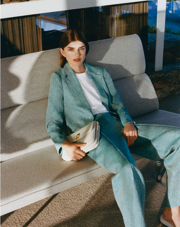 Image of model pictured lounging on a sofa wearing a green linen two-piece suit.